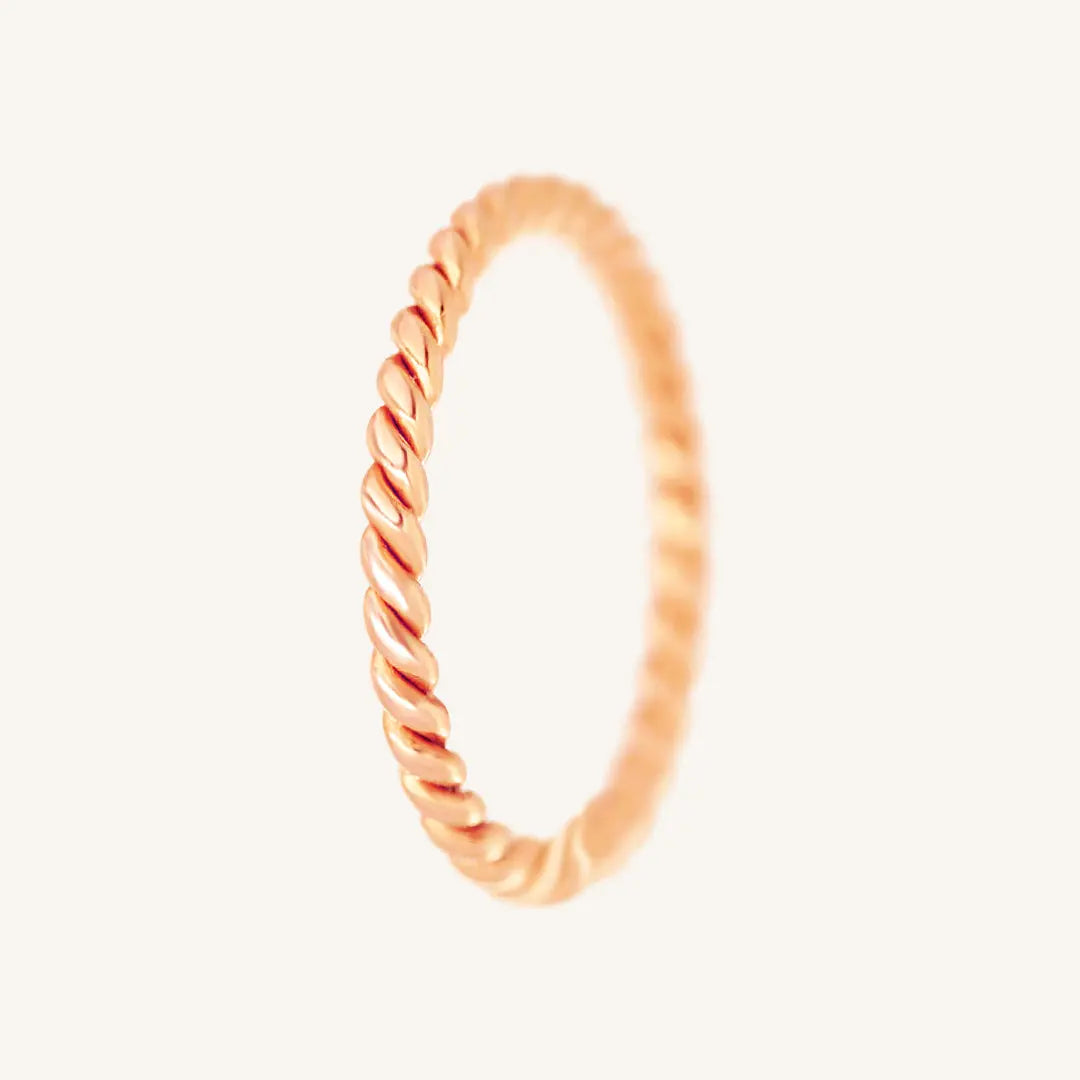 A rose gold-coloured stacking ring with a twisted design, displayed against a white background.