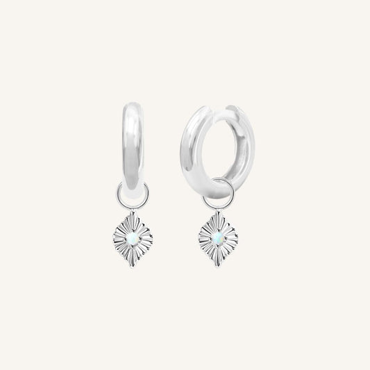 A pair of silver hoops with diamond shaped hoop charms featuring a faux opal