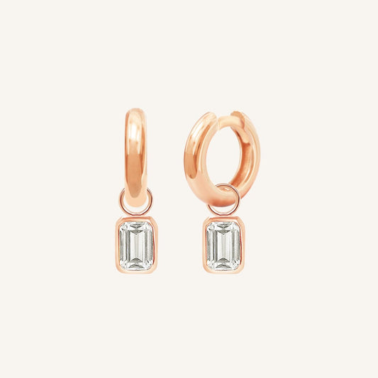 A pair of gold-colored hoop earrings with transparent crystal embellishments.