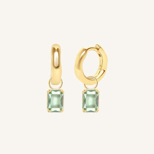 Gold hoop earrings with green gemstones on a white background
