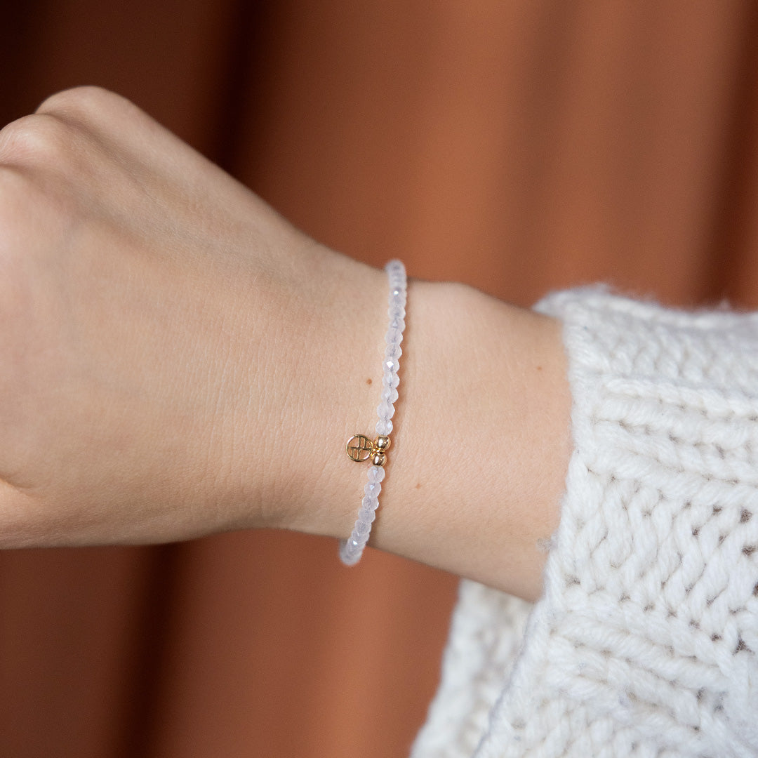 Close-up of a wrist wearing a delicate bracelet against a blurred background