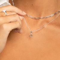 A silver anchor charm with a white cubic zirconia