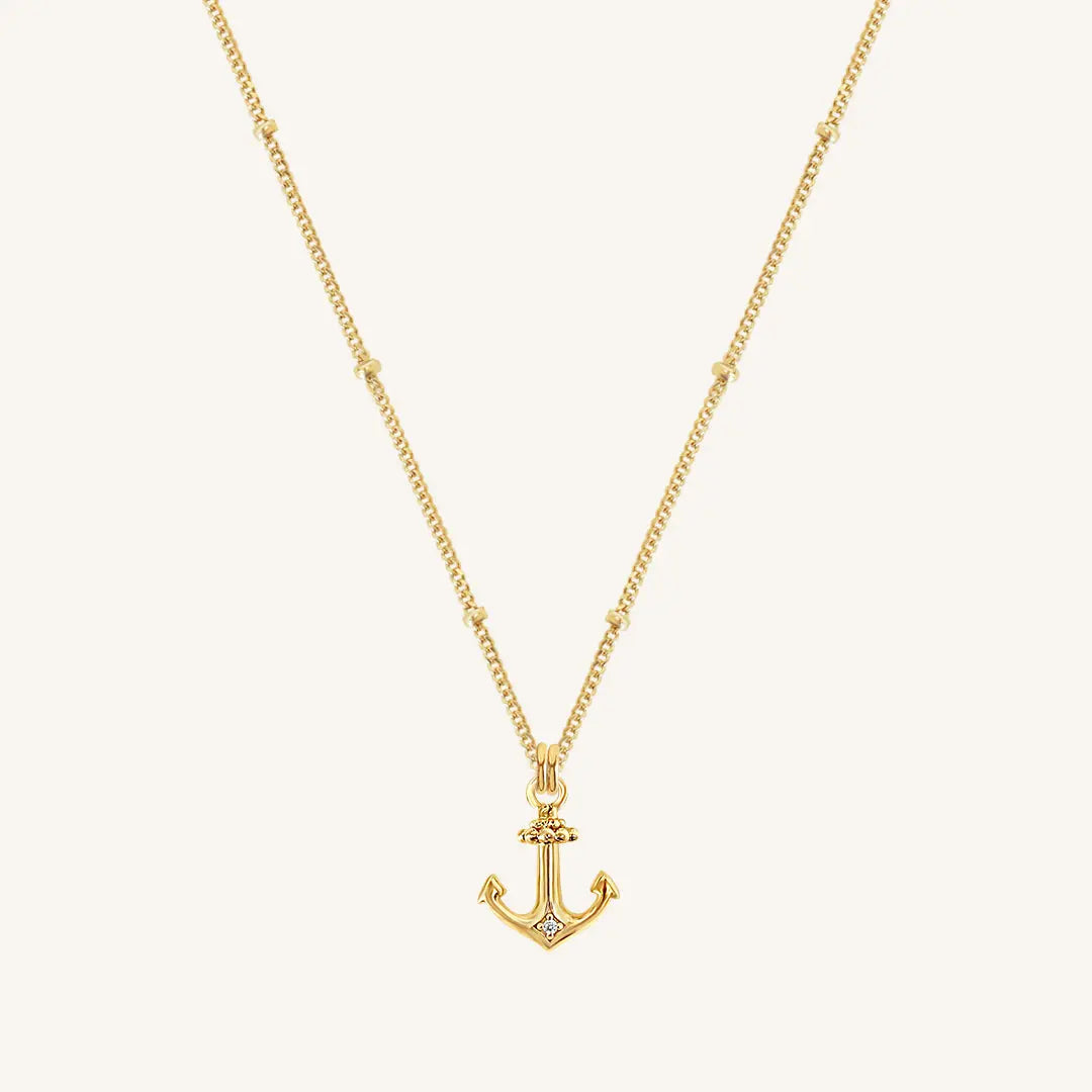 A gold-tone anchor necklace with a small, detailed anchor pendant on a chain.