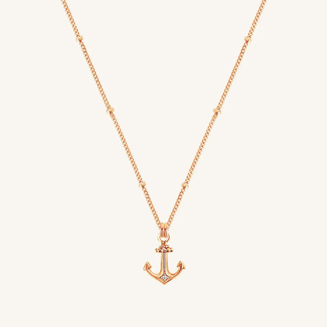 A rose-tone anchor necklace with a small, detailed anchor pendant on a chain.