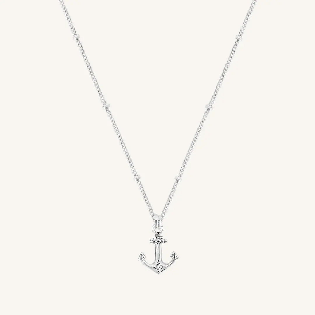 A silver-tone anchor necklace with a small, detailed anchor pendant on a chain.