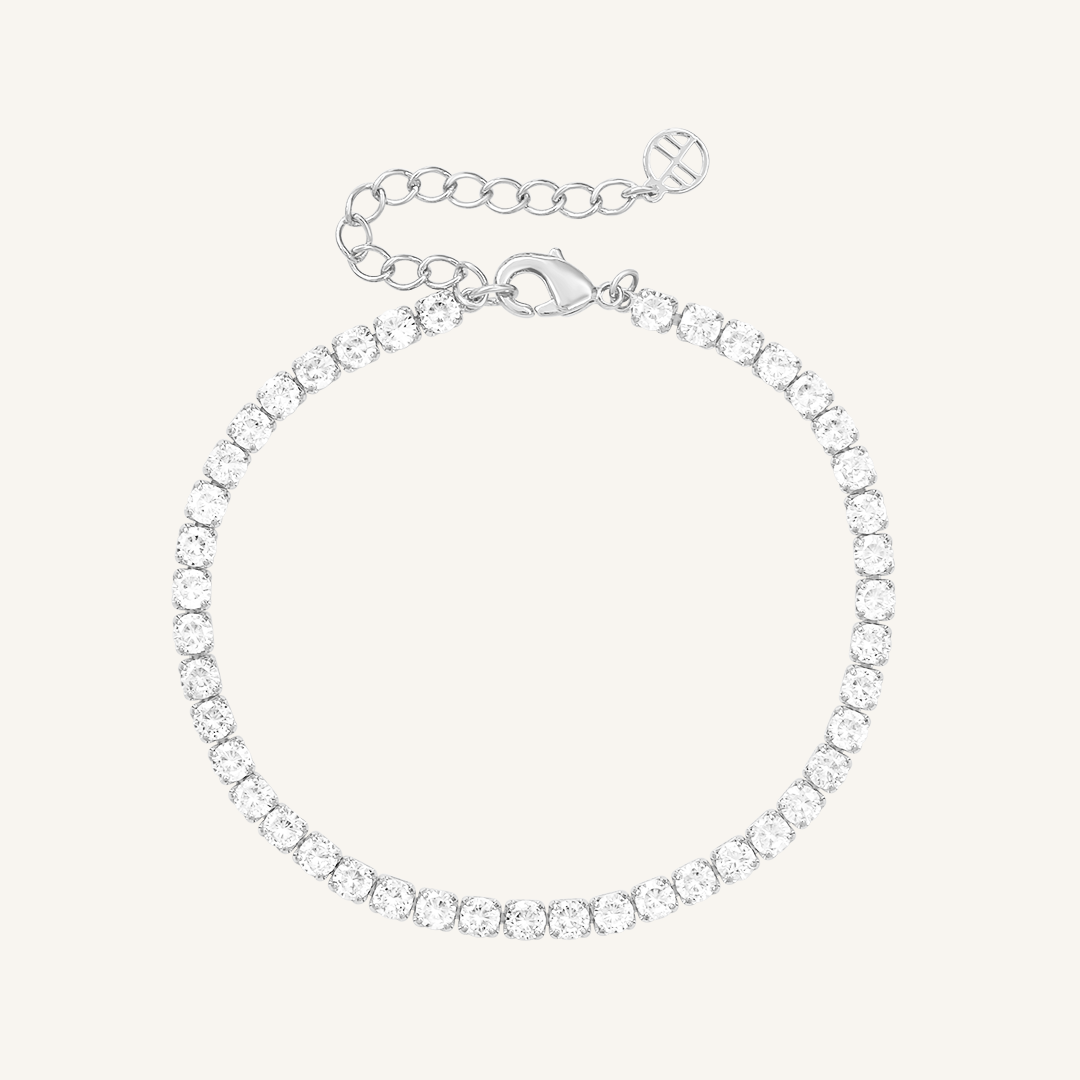 A silver-coloured tennis bracelet with clear cubic zirconias linked together, featuring a extender chain for adjustable length.
