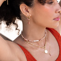 Gold hoop charms with pink gemstones on a white background