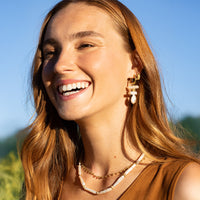 Pair of silver hoop earrings with teardrop-shaped pearls on a white background