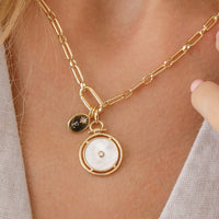 Silver pendant with a circular design and central gemstone on a white background