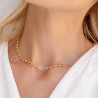 Gold necklace with small beads on a light beige background