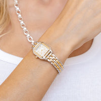 A luxurious coloured metal band watch with a square face and analog display.