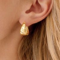 A pair of silver chunky hoop earrings on a white background.
