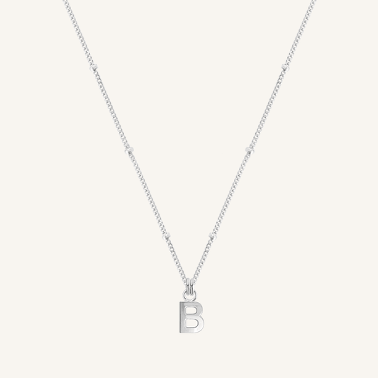 Silver necklace with a 'B' pendant on a light gray background