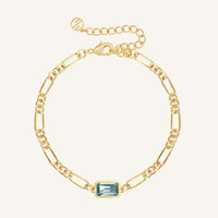 Gold bracelet with a blue gemstone on a white background