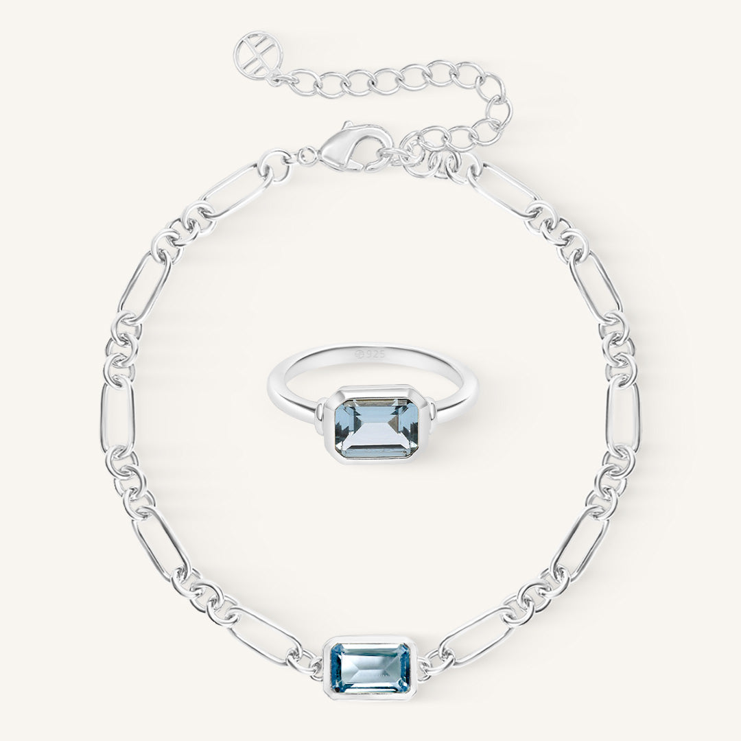 Silver bracelet and ring set with blue gemstones on a white background