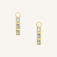 Gold hoop charms with blue gemstones on a white background