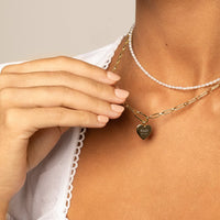 A silver heart-shaped charm with engraved initials and a date