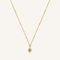 Gold necklace with a small pendant on a light beige background