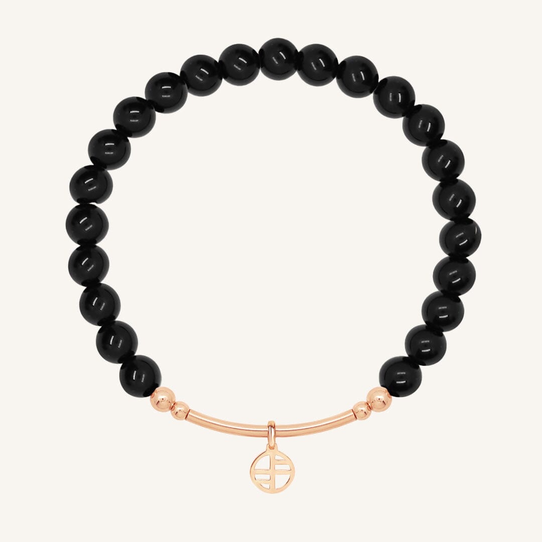 Black beaded bracelet with a rose gold bar on a white background