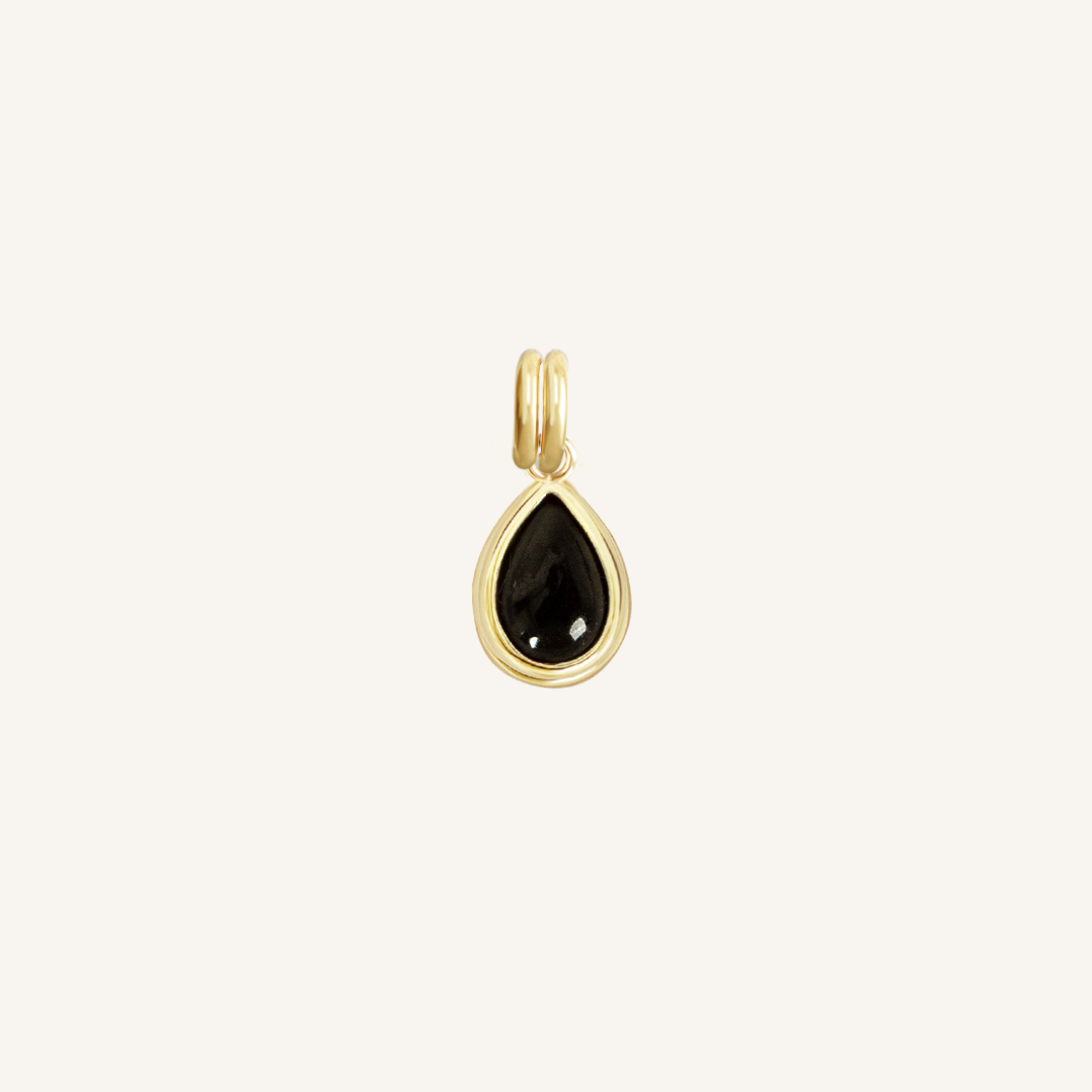 A gold charm with a teardrop-shaped black onyx stone.