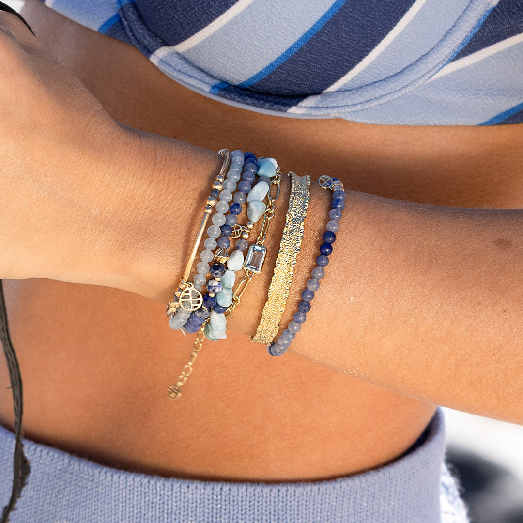 Close-up of a wrist wearing multiple bracelets with a blurred background