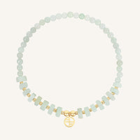 Bracelet with light green beads and gold accents on a white background