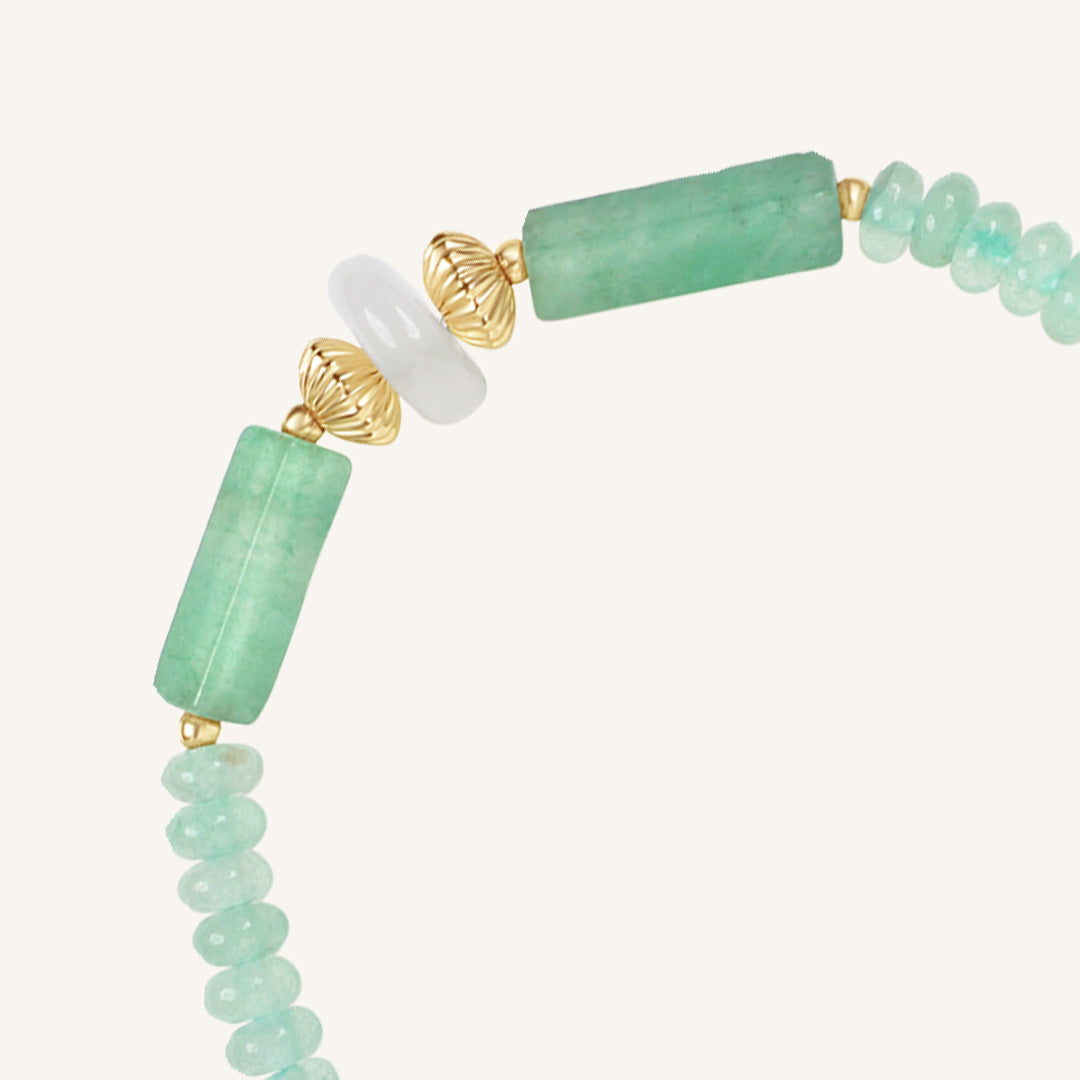 Bracelet with green beads and gold accents on a white background