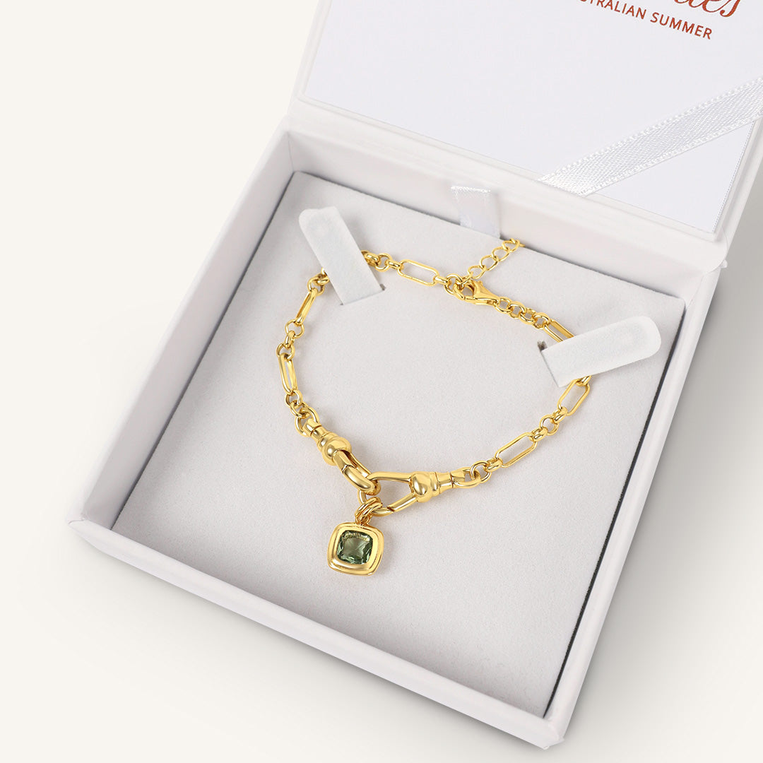 Gold bracelet with a green gemstone in a white box