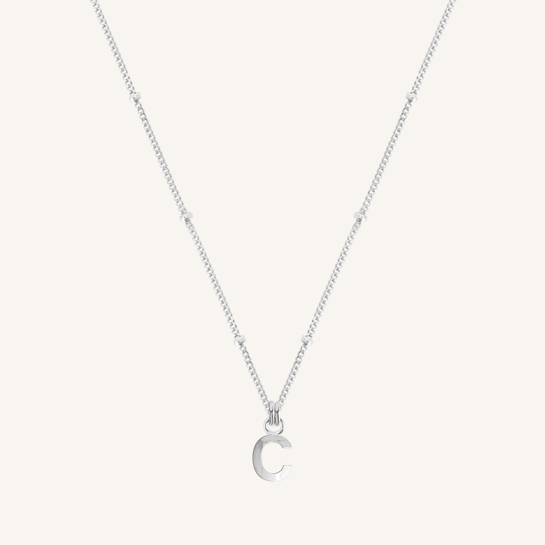 Silver necklace with a 'C' pendant on a light gray background