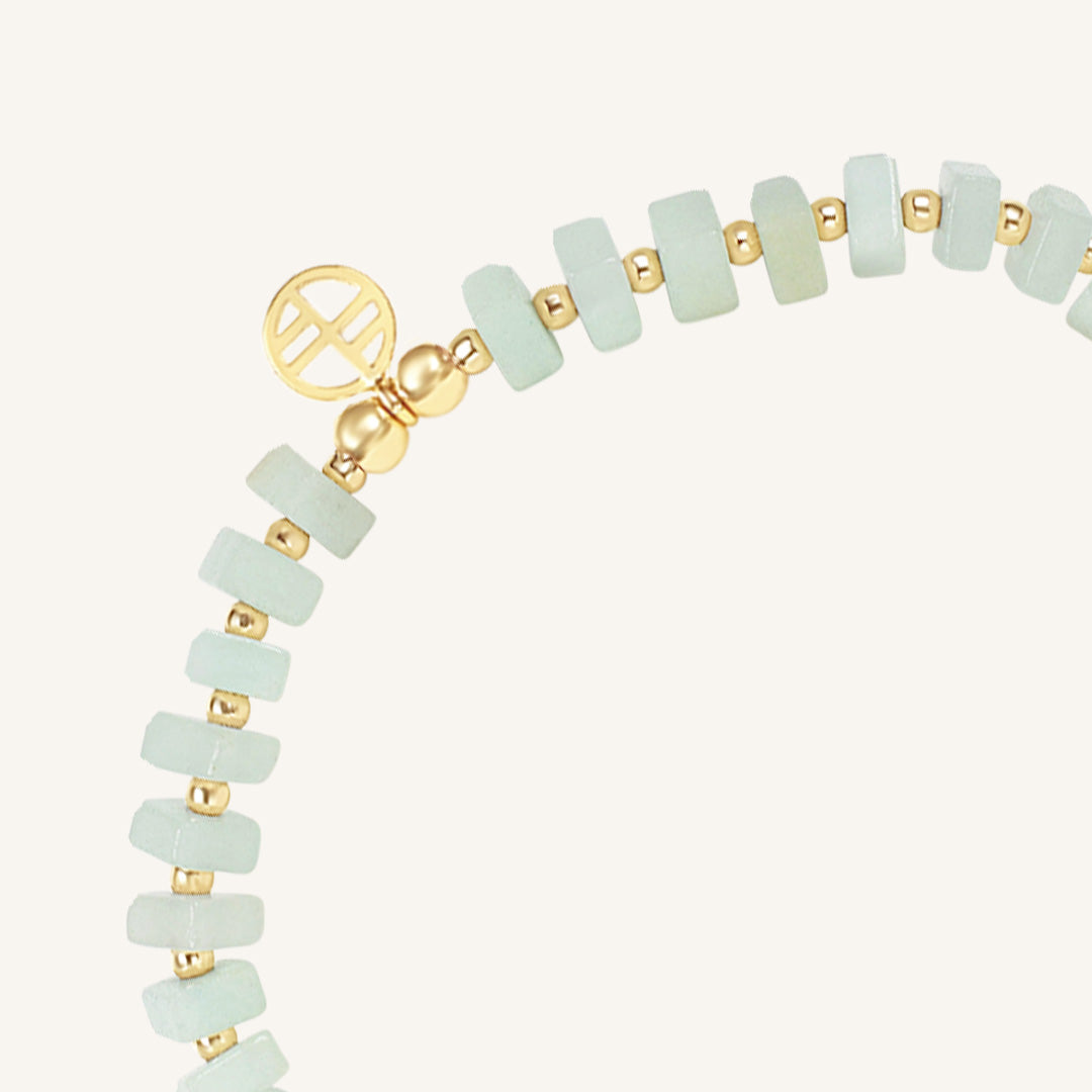 Bracelet with light green beads and gold accents on a white background