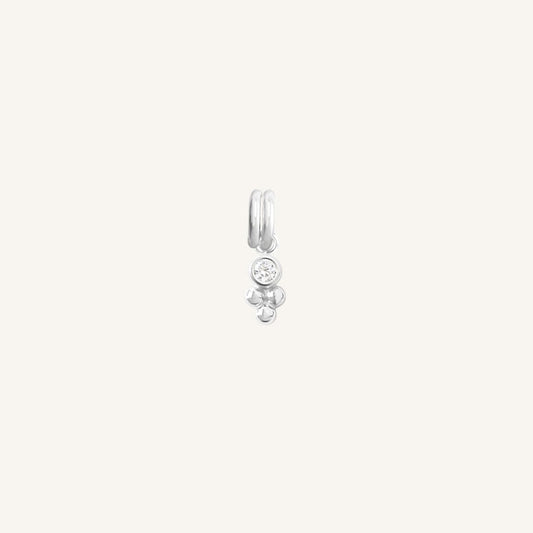 A small silver charm featuring a cubic zirconia and a floral design.