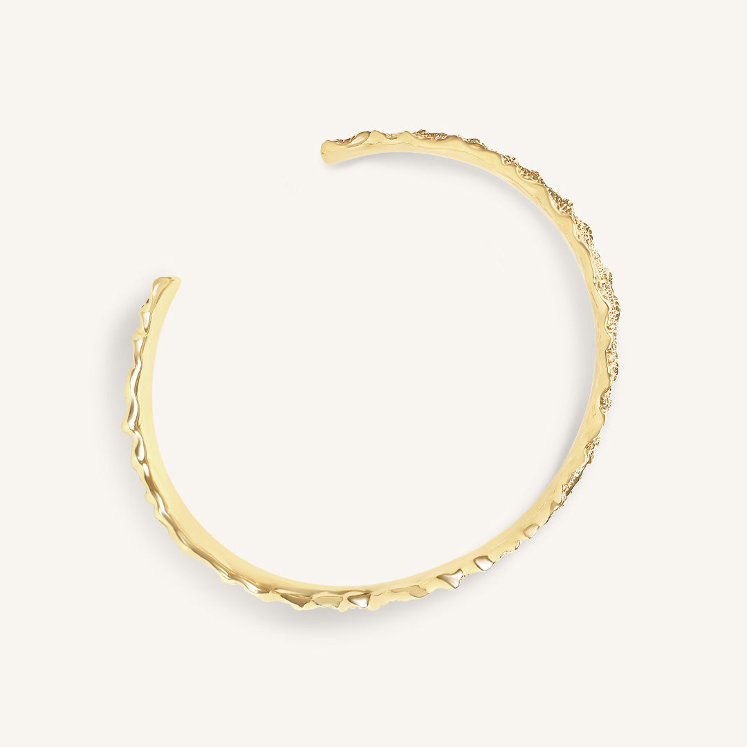 Gold bracelet on a light gray background