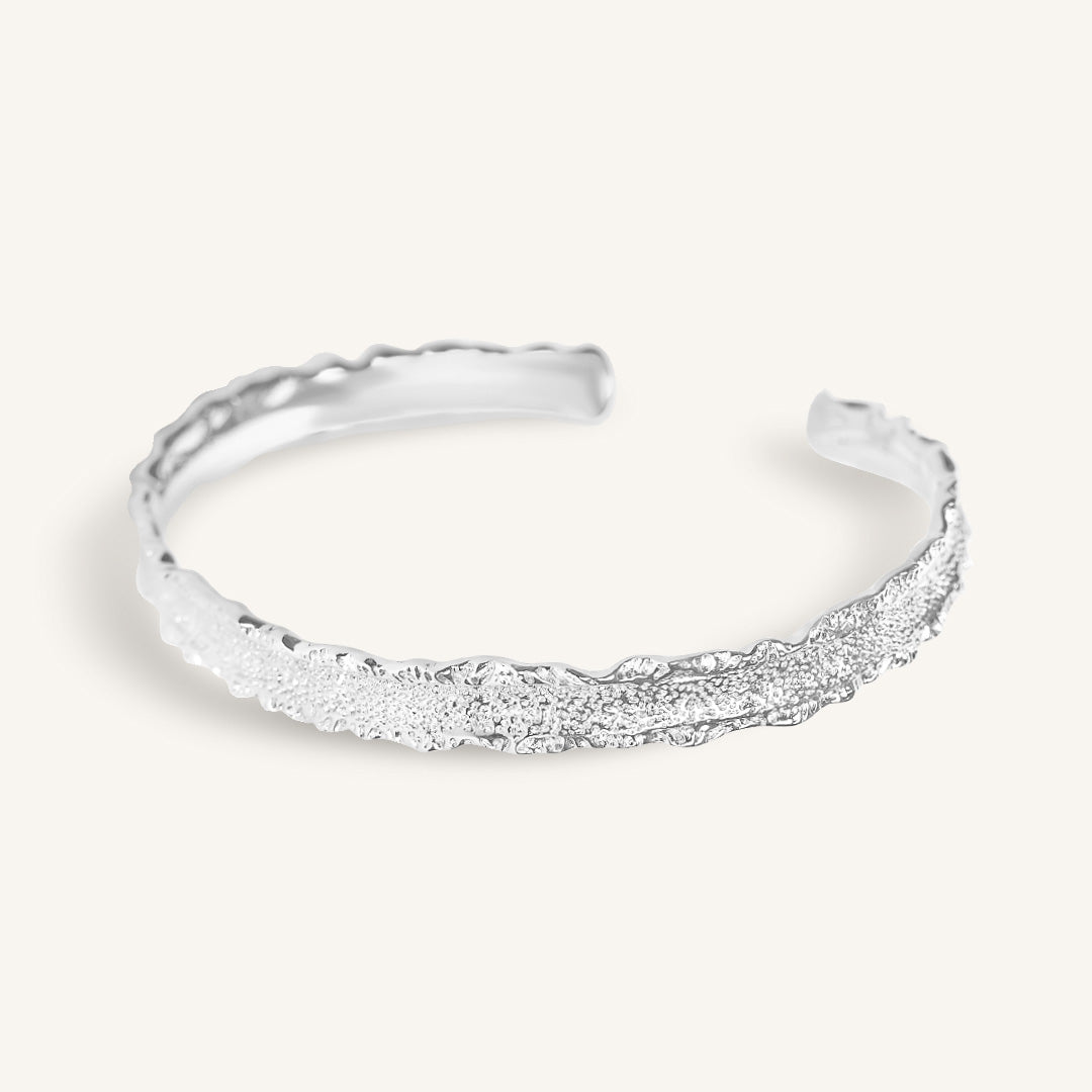 Silver bracelet with textured design on a white background