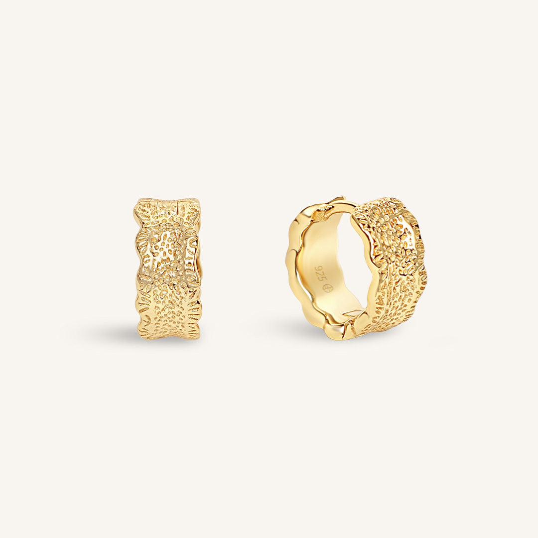 Gold hoop earrings on a light beige background