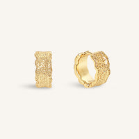 Gold hoop earrings on a light beige background
