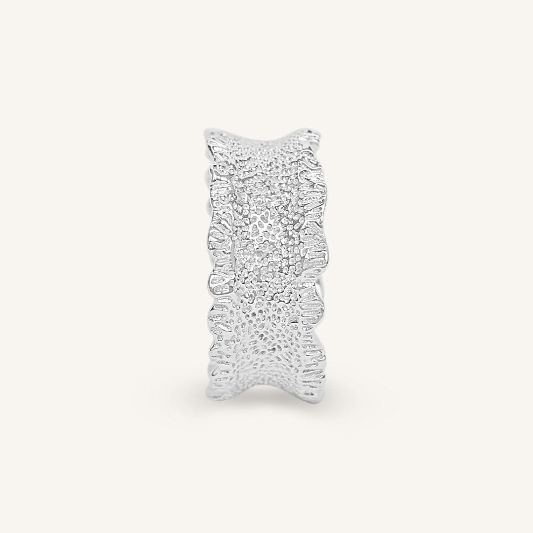 Silver ring with intricate design on a white background