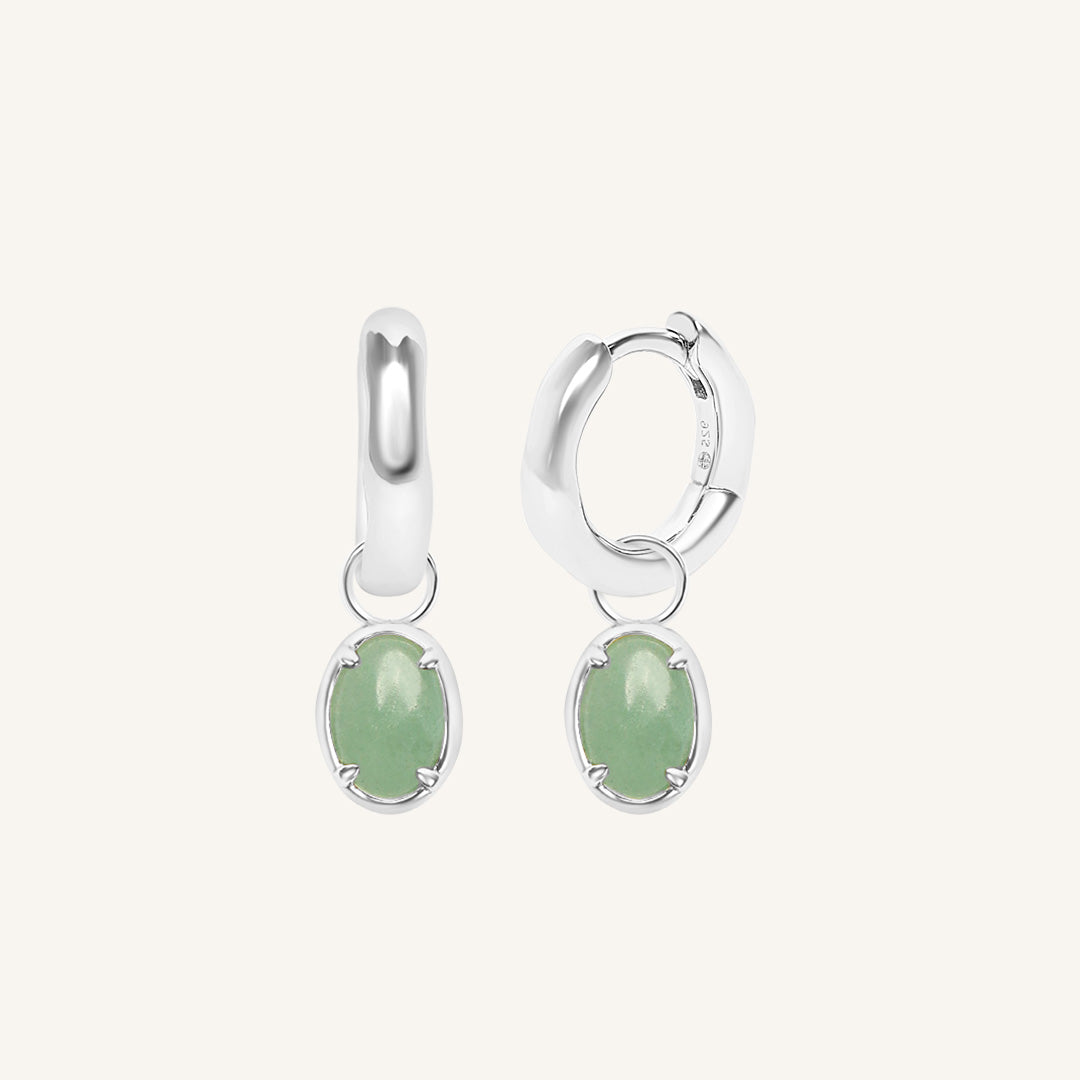 Silver hoop earrings with green gemstones on a white background
