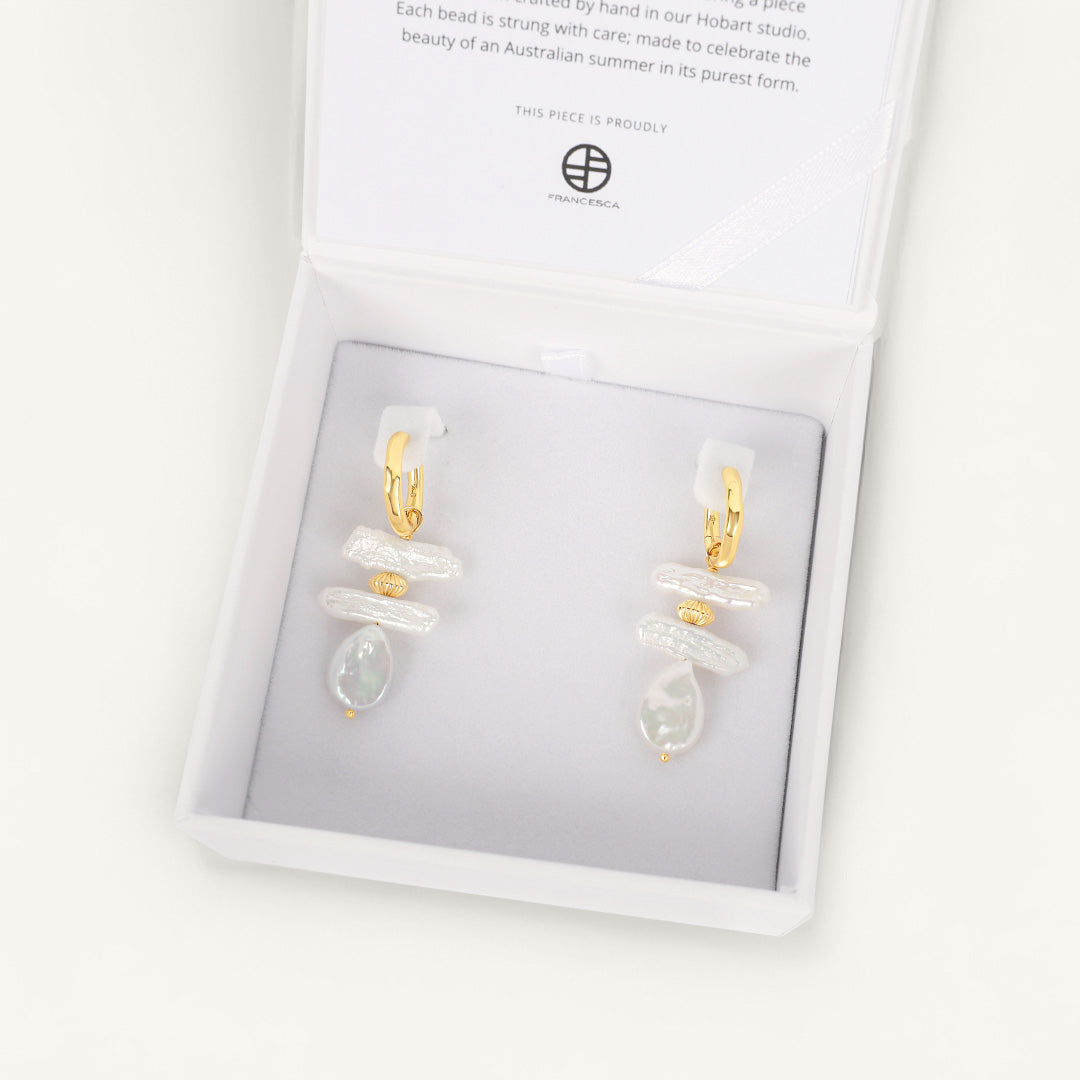 Pair of earrings in a white box with a visible brand logo.