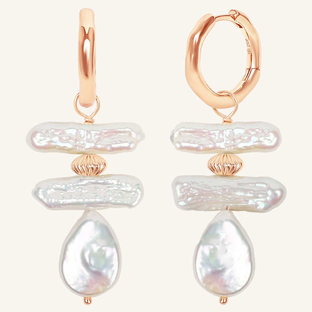 Rose gold hoop earrings with layered pearl drops on a white background