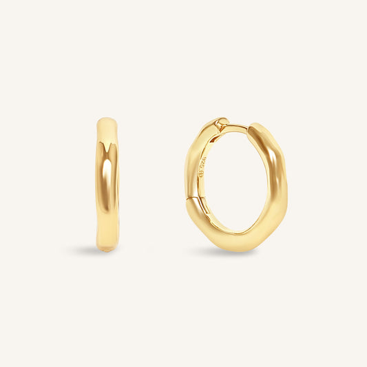 Gold hoop earrings on a light beige background