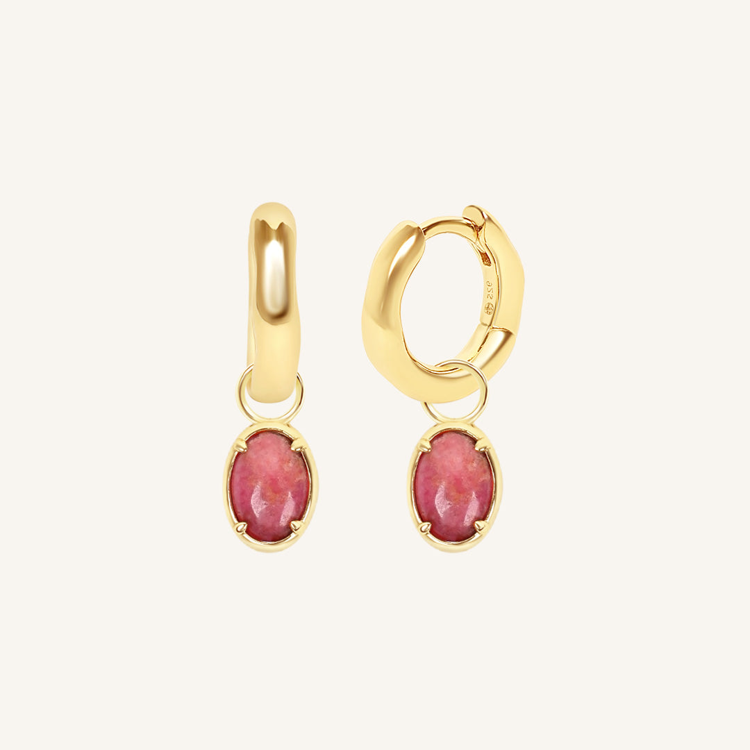 Gold hoop earrings with pink gemstones on a white background