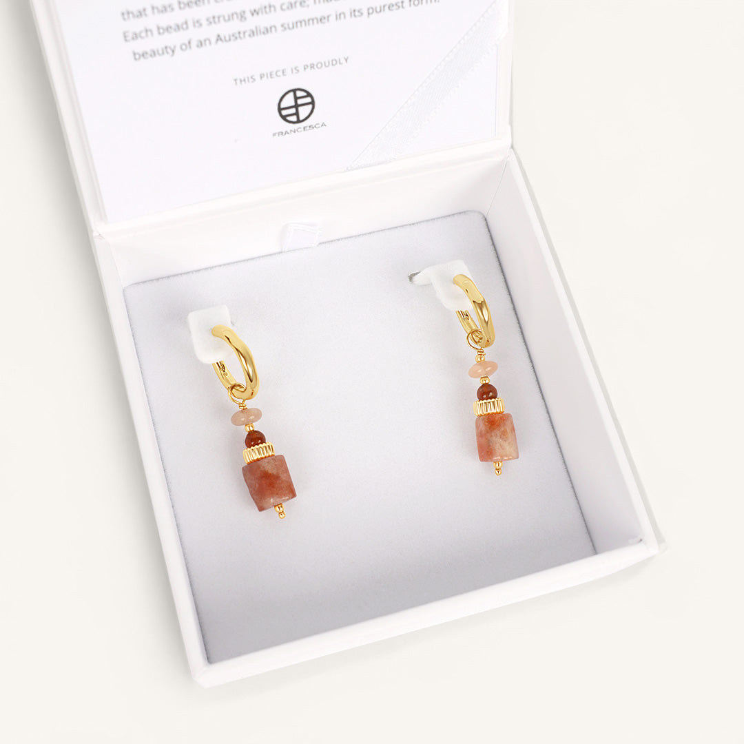 Pair of earrings with gold and brown beads in a white box