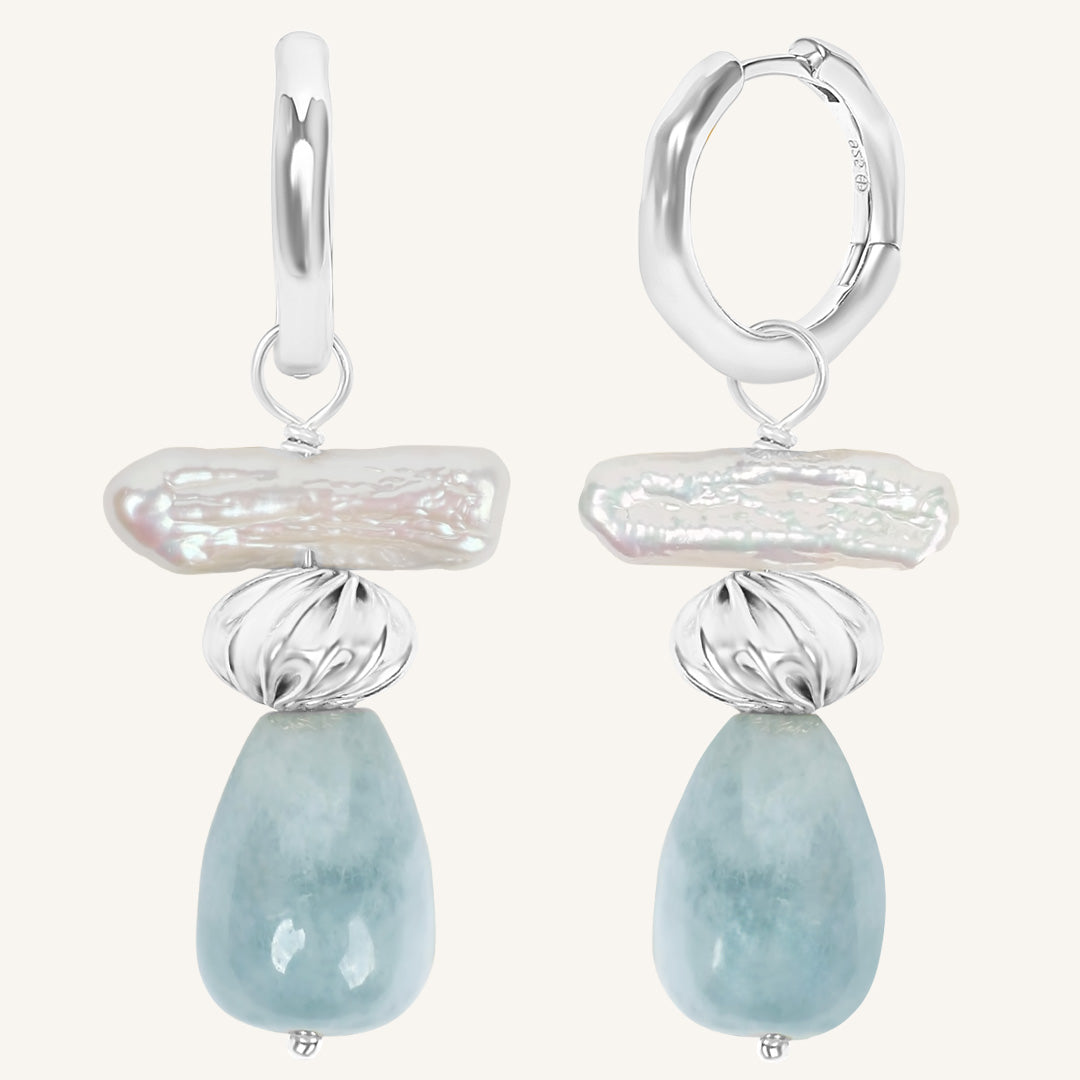 Pair of earrings with silver and light blue stone design on a white background