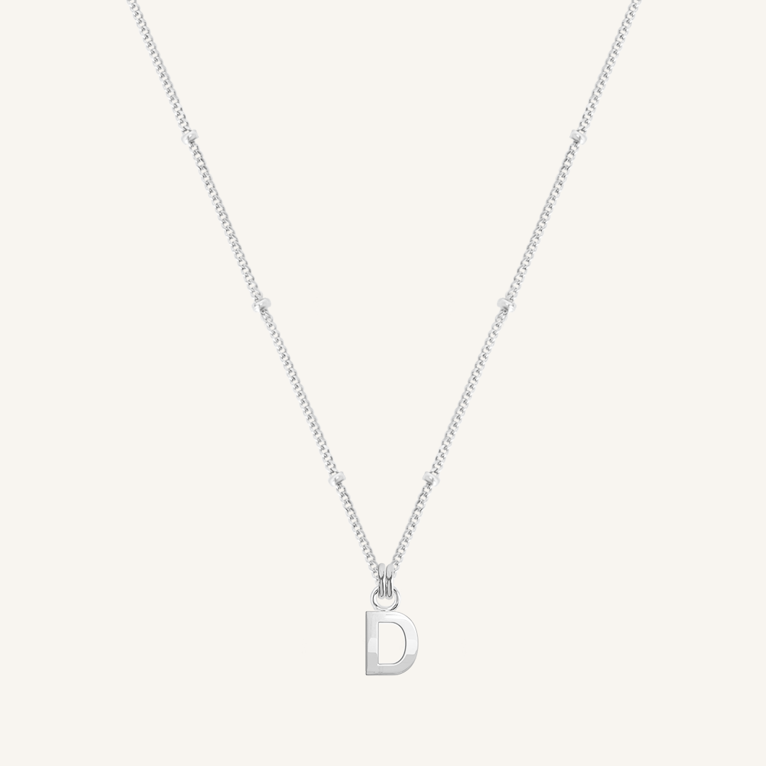 Silver necklace with a 'D' pendant on a light gray background