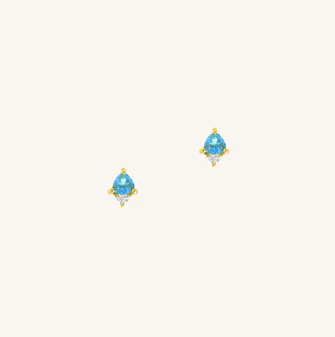 A gold pair of stud earrings featuring a blue cubic zirconia, representing December.