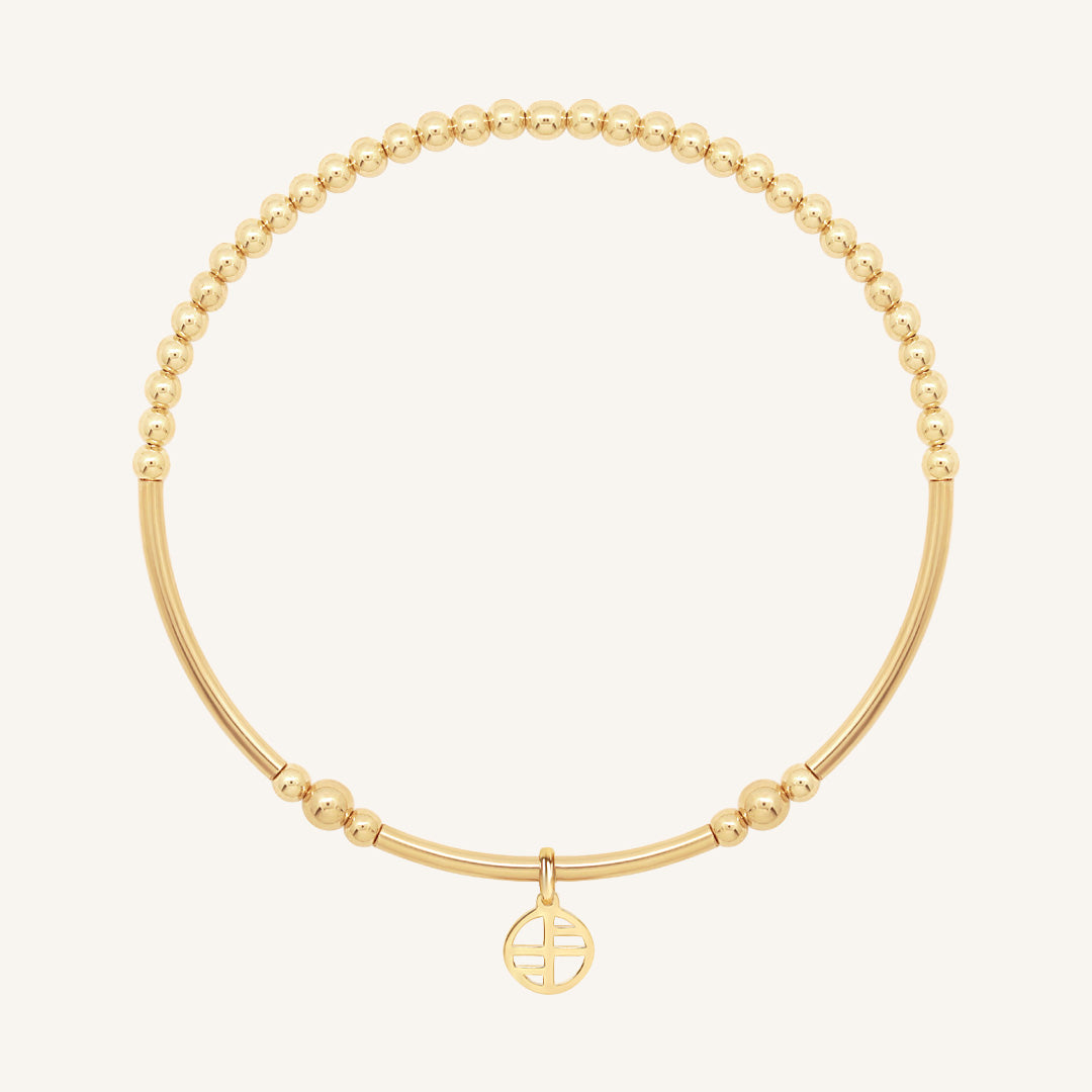 Gold bracelet with a small round charm on a white background