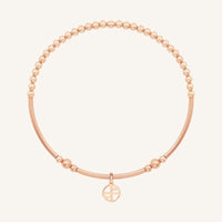 Rose gold bracelet with a small charm on a white background