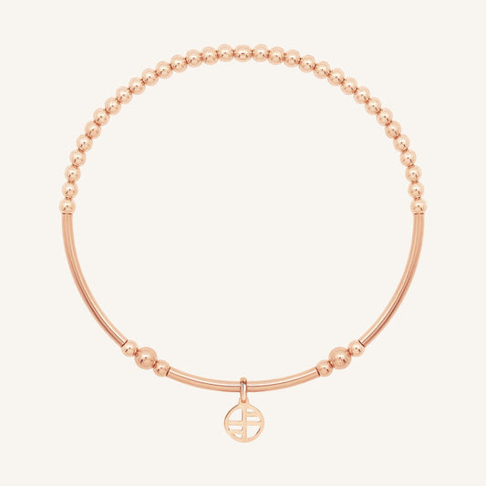Rose gold bracelet with a small charm on a white background