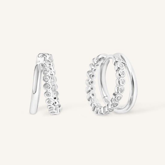 Silver hoop earrings with small stones on a white background