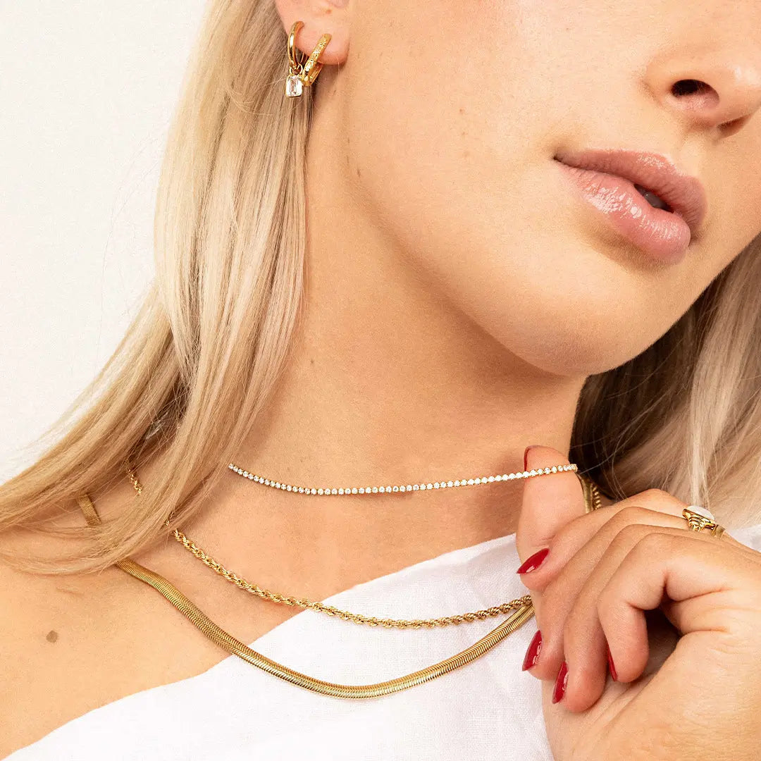 A tennis chain necklace with gold metal tone, worn on neck